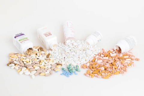 Various pills and tablets distributed around open medicine bottles