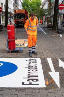 Application of road markings for a cycle lane, Rüttenscheider Straße in Essen, in the shopping and