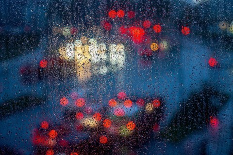 Rainy weather, road traffic, raindrops on a window pane, behind, blurred, lights of vehicles on a