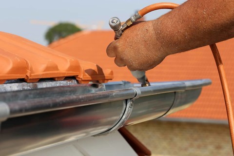 Roofer doing tinsmith work on a gutter