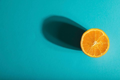 Ripe cut orange on blue pastel background. Top view, flat lay, copy space, hard light. Tropical,
