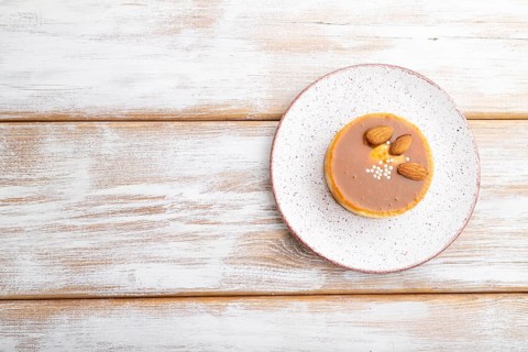 Sweet tartlets with almonds and caramel cream on a white wooden background. top view, flat lay,