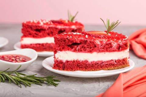 Homemade red velvet cake with milk cream and strawberry on a gray concrete background with red
