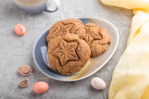 Homemade oatmeal cookies with a cup of cocoa and a yellow textile on a gray concrete background.