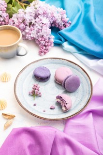 Purple macarons or macaroons cakes with cup of coffee on a white concrete background and