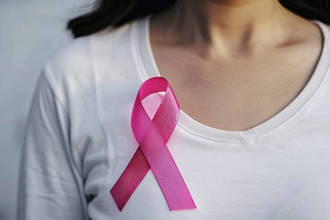 Pink breast cancer awareness ribbon attached to woman's white shirt. Generative AI, AI generated
