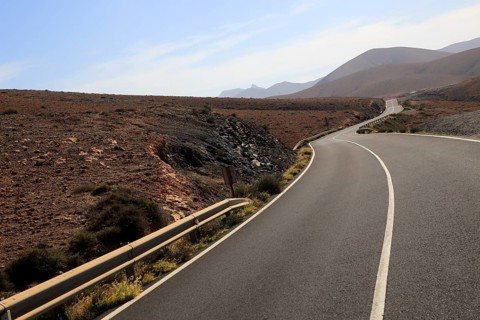 Tarmac road crossing barren desert mountainous land between Pajara and La Pared, Fuerteventura,
