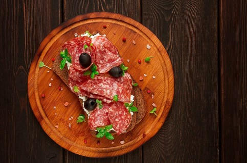 Sandwich, grain bread, with cream cheese and salami, black olives, micro-greens, top view,