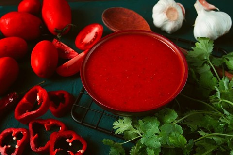 Tomato sauce, tomatoes and sweet pepper, Georgian Satsebeli sauce, with ingredients on a dark