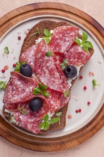 Sandwich, grain bread, with cream cheese and salami, black olives, micro-greens, top view,