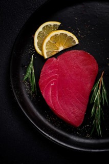 Fresh red tuna fillet, for steak, raw, top view, on a black plate, no people