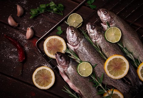 Raw rainbow trout, with lemon and herbs, on a wooden table, no people