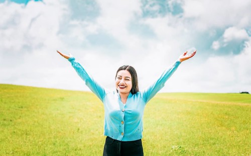 Portrait of beautiful girl spreading arms enjoying the countryside. Happy young woman spreading