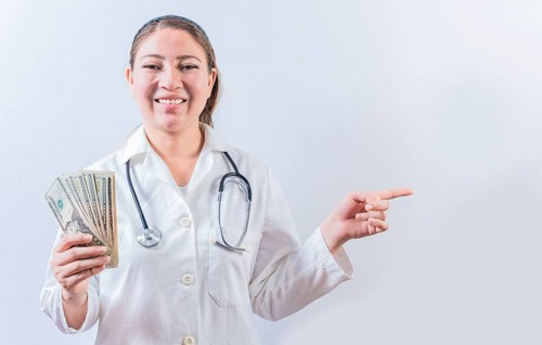 Happy female doctor holding money and pointing to side. Beautiful female doctor showing money and
