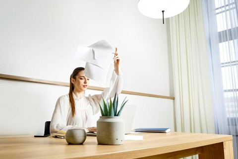 A woman is tired of monotonous work in the office and throws away documents