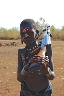 South Ethiopia, in Maco National Park, Mursi tribe, Mursi boy with painted face and rifle,