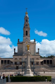 Large basilica with bell tower and statue in the foreground under a blue sky, Basilica of Our Lady