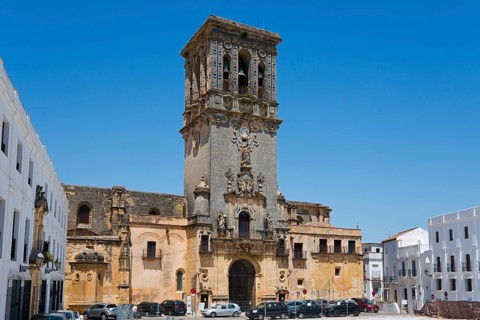A town square with an impressive bell tower and surrounding buildings in bright weather, Basilica