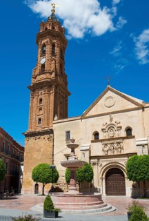 Church building with high tower and fountain on a sunny town square under a blue sky, Real