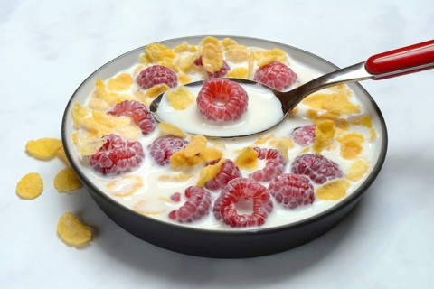 Raspberries and cornflakes with milk in a bowl, Rubus idaeus