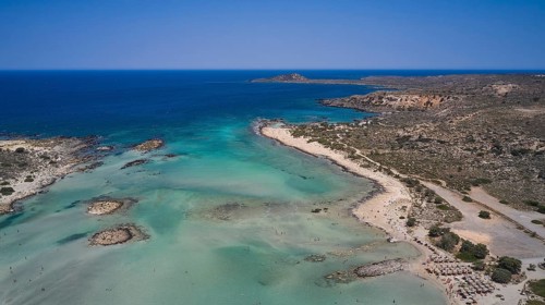 Overtourism, tourists on the beach, parasols, coastal landscape with blue water and several beaches