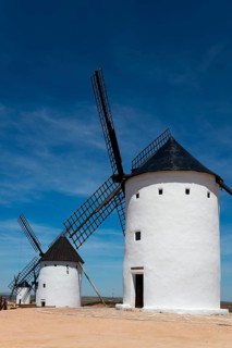 Three white windmills under a deep blue sky in a tranquil rural landscape on a sunny day, Alcazar