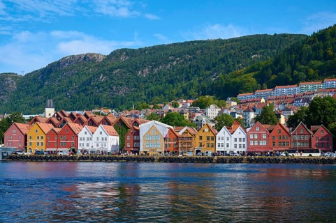 A picturesque town by the water with colourful traditional houses and green mountains in the