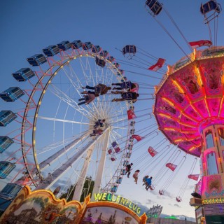 A funfair at dusk with illuminated chain carousel and Ferris wheel, Europa Rad, rides, wave flight,