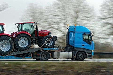 Truck, lorry, articulated lorry with new tractors driving fast on the A92 motorway, motion blur,