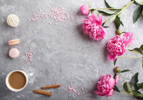 Pink peony flowers and a cup of coffee on a gray concrete background. Morninig, spring, fashion
