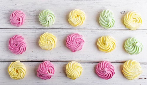 Set of colored meringues on white wooden background. top view, flat lay. geometric pattern