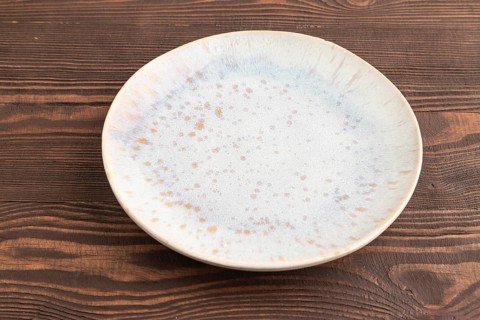 Empty blue and gold ceramic plate on brown wooden background. Side view, copy space