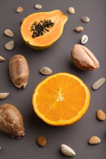 Ripe cut papaya, orange, seashells on gray pastel background. Side view, copy space. Tropical,