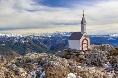 A lonely miniature chapel on the Hochgern summit in the Chiemgau mountains surrounded by rocks and