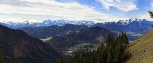 Panoramic view of the snow-covered Chiemgau mountains and green hills above the village of