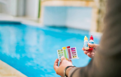 Hand holding tester kit to measure chlorine and ph in swimming pools. Person testing the PH of the