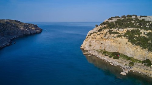 Drone shot, Rocky coast with a calm bay and blue water surrounded by natural beauty and sky,