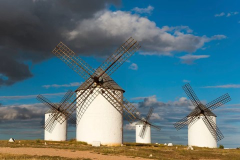 Windmills in a vast landscape under a sky with dramatic clouds and sunlight, Windmills, Campo de