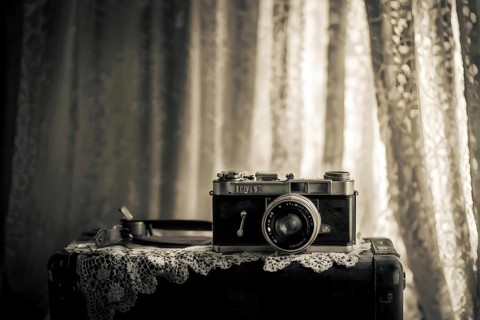 Vintage film camera surrounded by black and white photos in soft sunlight, AI generated