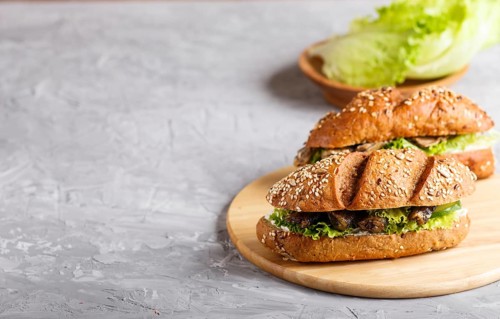 Sprats sandwiches with lettuce and cream cheese on wooden board on a gray concrete background. side