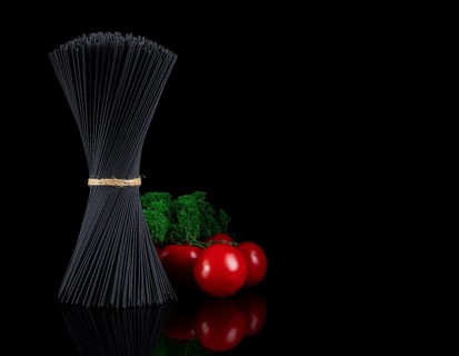 Bouquet, black spaghetti Nori, with ingredients, tomatoes and basil, on a black background,