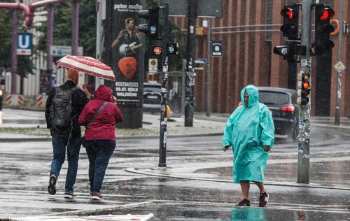 A man with a rain cape stands on a street in heavy rainfall, Berlin, 22/06/2024, Berlin, Berlin,