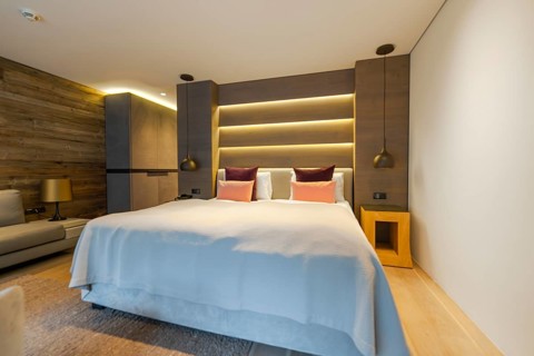 Modern bedroom with large bed, backlit wall and wood panelling, Mayrhofen, Zillertal, Austria,