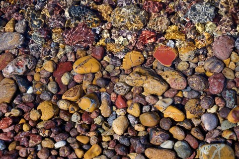 Colourful pebbles under clear water, forming a varied texture and natural patterns, Lambi beach,