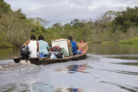 Local Bolivians moving furniture by canoe with outboard motor on the Yacuma River in the Pampas del