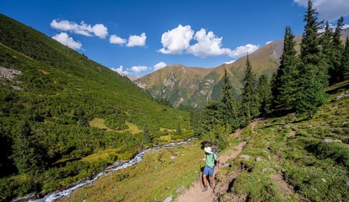 Mountaineers on a hiking trail by a mountain stream, Keldike Valley on the way to the Ala Kul Pass,