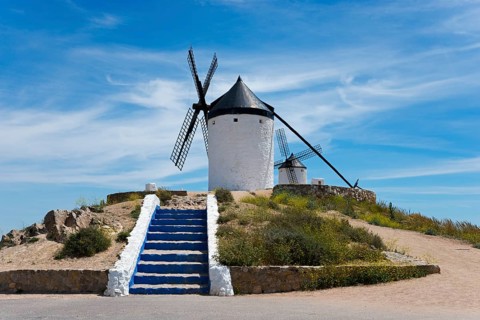 White windmill on a hill with blue steps and a clear blue sky in the background, Consuegra, Toledo,