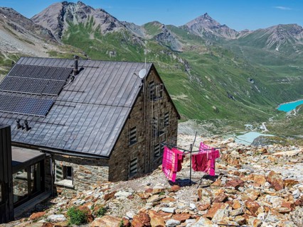 Colored bed linen dries in the sun, mountain hut Cabane de Moiry, lake Lac de Moiry in the back,