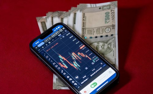 Stock market graph or chart display on a mobile phone against Indian 500 rupee paper currency note