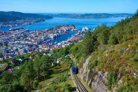 Panoramic view of Bergen with harbour on a clear day, cable car ascending the wooded mountain,
